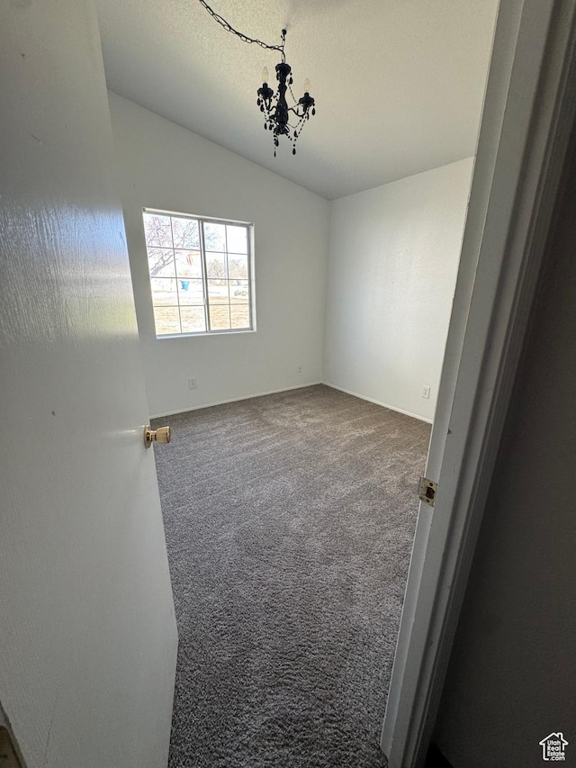 carpeted spare room with lofted ceiling and baseboards