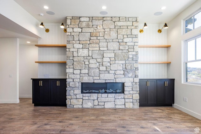 unfurnished living room with a fireplace, baseboards, wood finished floors, and recessed lighting