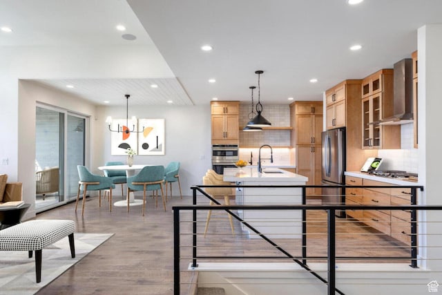 kitchen with wall chimney range hood, tasteful backsplash, a sink, light wood-type flooring, and recessed lighting
