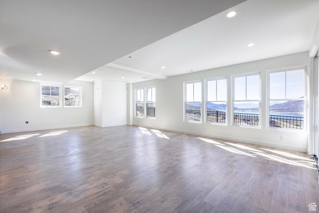 unfurnished living room featuring recessed lighting, wood finished floors, and baseboards
