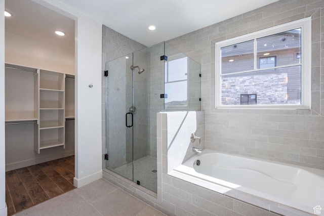 bathroom with a shower stall, a bath, a healthy amount of sunlight, and a walk in closet