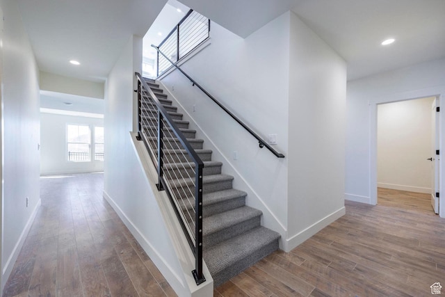 staircase featuring recessed lighting, wood finished floors, and baseboards
