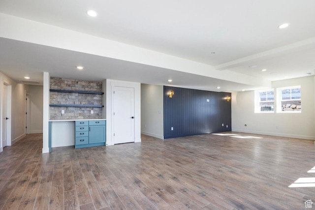 below grade area with wood finished floors, baseboards, and bar