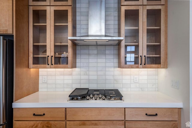 kitchen with glass insert cabinets, backsplash, appliances with stainless steel finishes, and wall chimney range hood