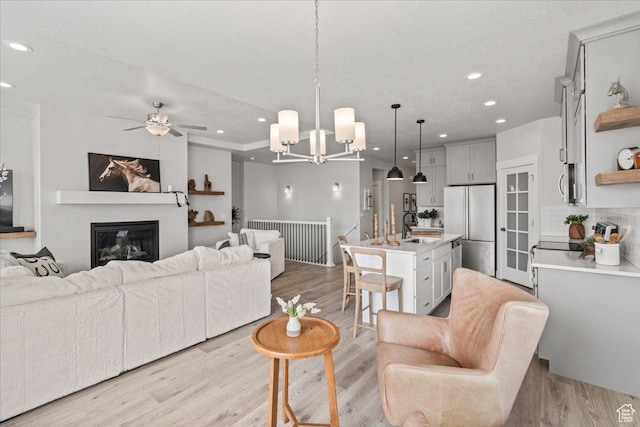 6079 W Teton Village Dr Unit 106, Herriman, UT 84096 - living area with ceiling fan with notable chandelier, light wood-style flooring, a glass covered fireplace, and recessed lighting