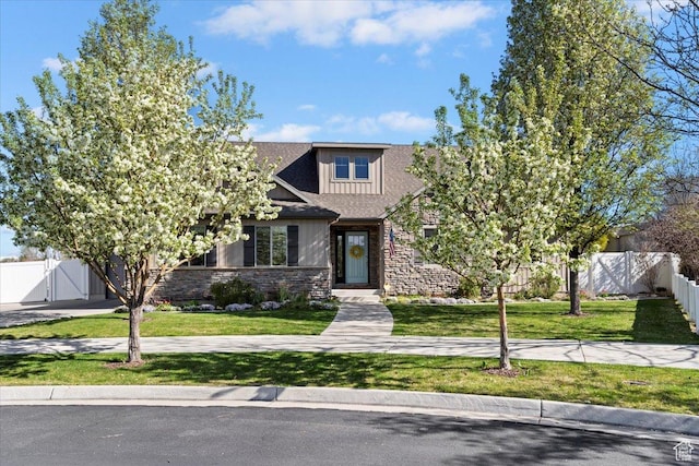 view of front of home featuring stone siding, a front lawn, and fence