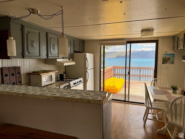 2904 S Edgemont Dr, Garden City, UT 84028 - kitchen with white appliances, wood finished floors, a water view, a peninsula, and under cabinet range hood
