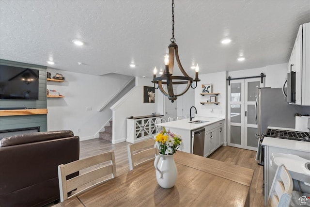 interior space with light wood-style flooring, a barn door, a notable chandelier, stairway, and a fireplace