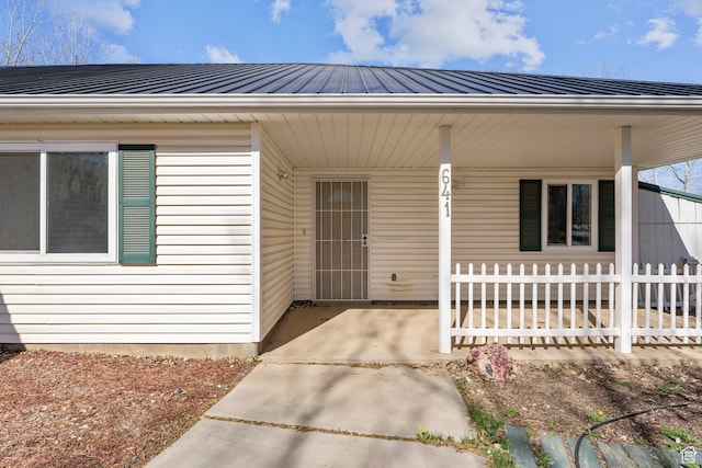 view of exterior entry with covered porch and fence