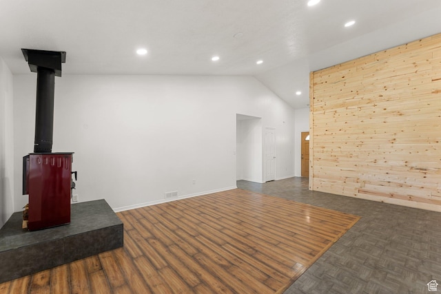 unfurnished living room with recessed lighting, dark wood-style floors, vaulted ceiling, a wood stove, and visible vents
