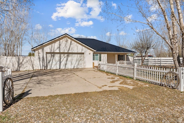 view of front of house with concrete driveway, an attached garage, fence private yard, and metal roof