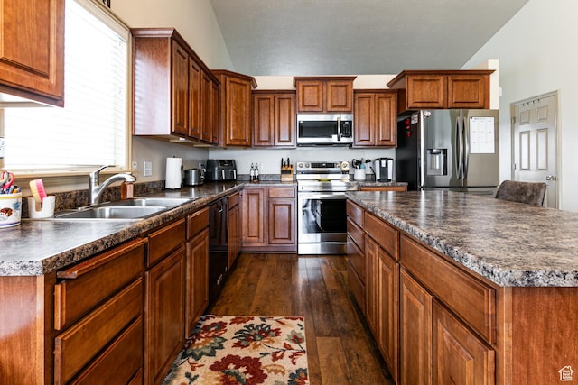 6576 W Oak Bridge Dr, West Jordan, UT 84081 - kitchen with appliances with stainless steel finishes, a sink, dark wood finished floors, dark countertops, and vaulted ceiling