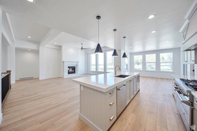 1910 W Bonneville Ln, Kaysville, UT 84037 - kitchen with stainless steel appliances, a glass covered fireplace, visible vents, a sink, and open floor plan