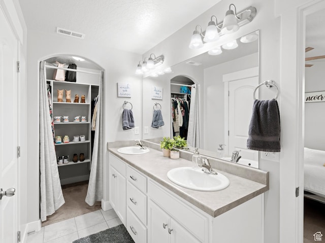 bathroom featuring tile patterned flooring, visible vents, a sink, and a walk in closet