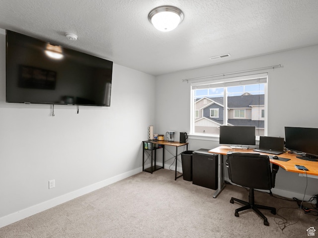 office area with visible vents, baseboards, a textured ceiling, and light colored carpet