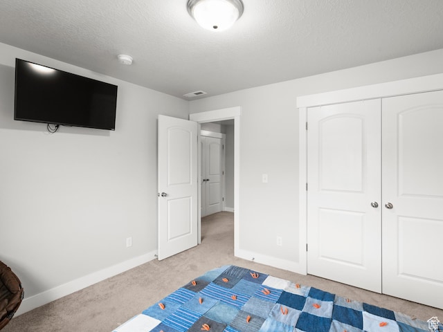 unfurnished bedroom with visible vents, a closet, baseboards, a textured ceiling, and carpet flooring