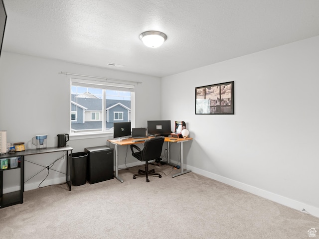 office featuring visible vents, light carpet, baseboards, and a textured ceiling