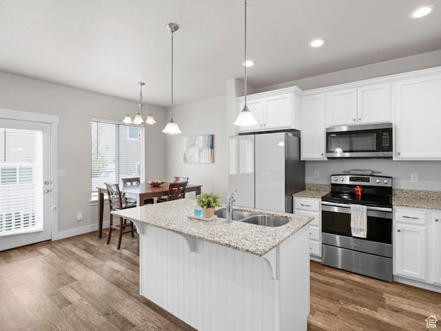 kitchen featuring stainless steel appliances, a sink, recessed lighting, white cabinetry, and wood finished floors