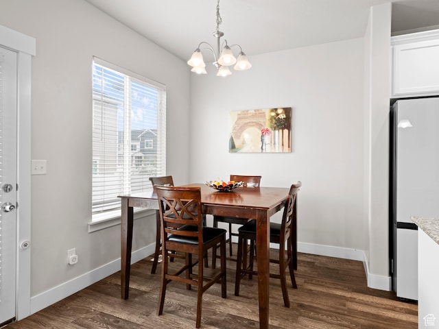 dining room featuring dark wood finished floors, an inviting chandelier, and baseboards