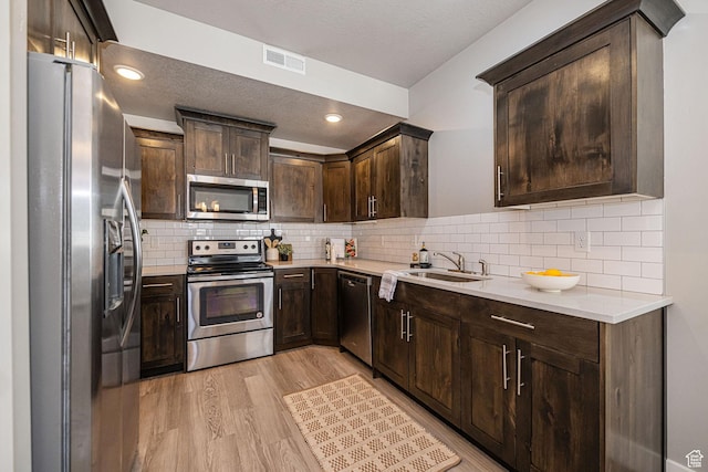 2276 W 2625 S Unit 110, West Haven, UT 84401 - kitchen featuring visible vents, a sink, light wood-type flooring, dark brown cabinetry, and appliances with stainless steel finishes
