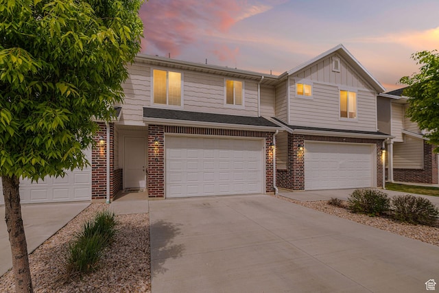 townhome / multi-family property with an attached garage, driveway, and brick siding