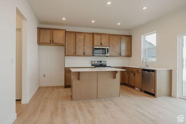 3651 N Oak Blvd Unit 337, Eagle Mountain, UT 84005 - kitchen with stainless steel appliances, light wood-style floors, a kitchen island, and brown cabinets