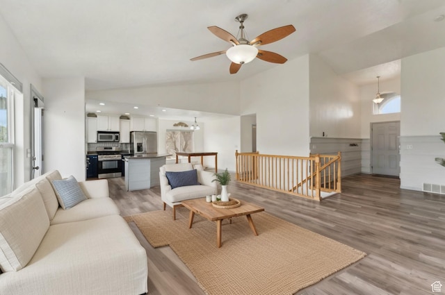 living area featuring high vaulted ceiling, a ceiling fan, light wood finished floors, and visible vents