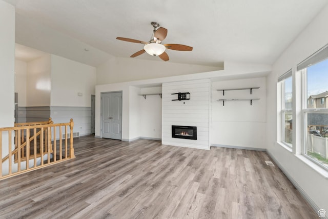 unfurnished living room featuring lofted ceiling, wood finished floors, visible vents, a large fireplace, and ceiling fan