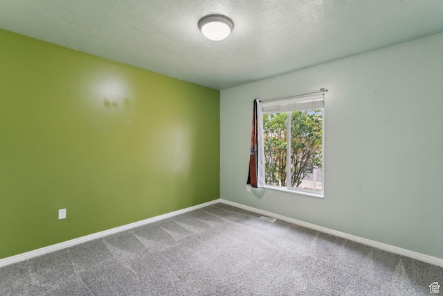 unfurnished room featuring baseboards, carpet flooring, a textured ceiling, and visible vents