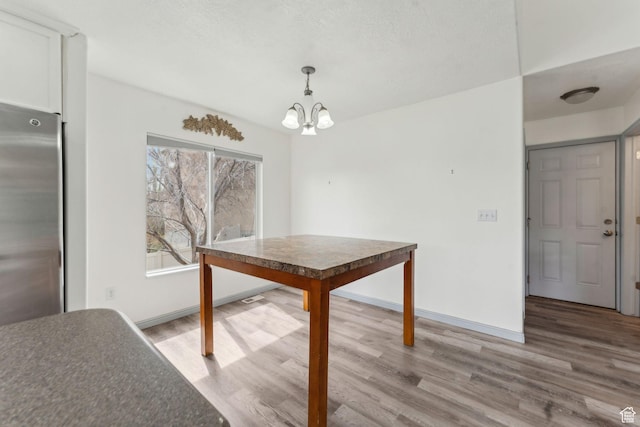 unfurnished dining area with wood finished floors, baseboards, and an inviting chandelier