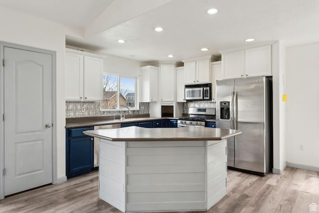 kitchen featuring blue cabinets, decorative backsplash, stainless steel appliances, light wood finished floors, and white cabinets