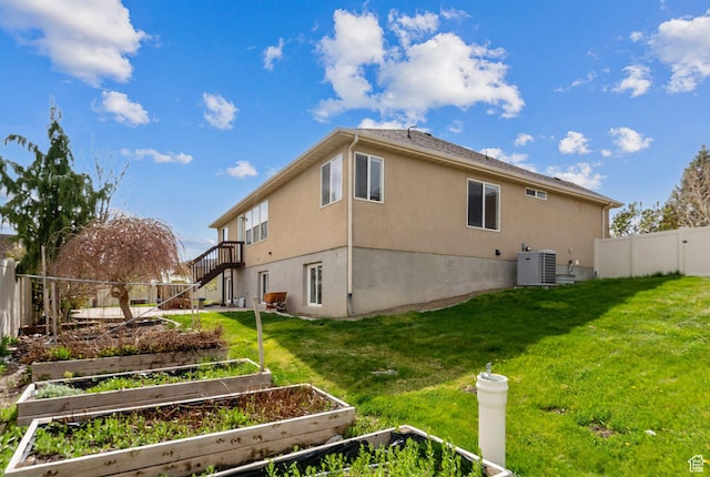 exterior space with central AC, a vegetable garden, a fenced backyard, a yard, and stairs