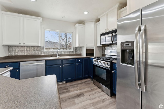 kitchen featuring white cabinets, blue cabinetry, a sink, light wood-style floors, and appliances with stainless steel finishes