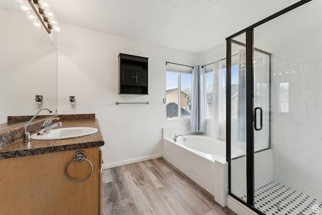 bathroom featuring a bath, a shower stall, vanity, and wood finished floors