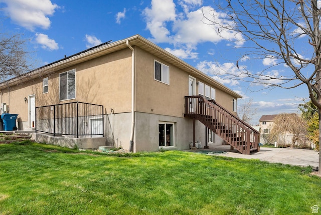 back of property featuring stucco siding, a patio area, a yard, and stairs