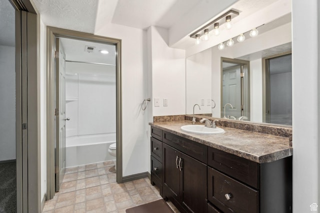 full bath featuring toilet, visible vents, baseboards, stone finish floor, and vanity