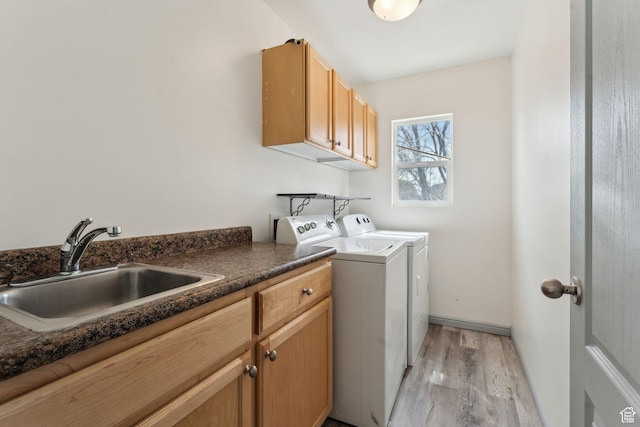 clothes washing area with light wood-type flooring, washer and clothes dryer, a sink, and cabinet space