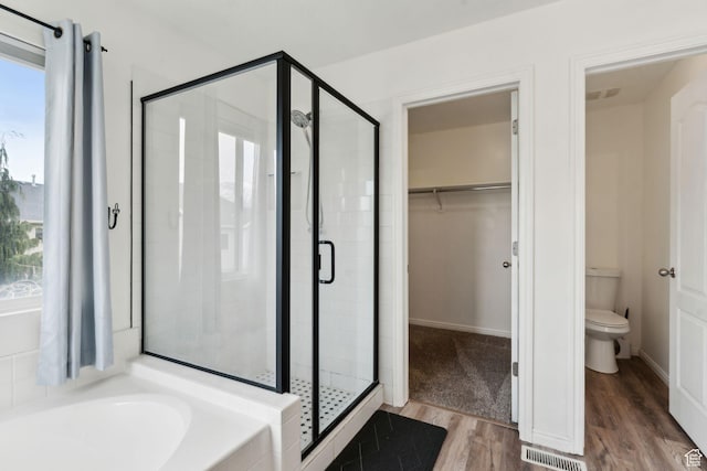 full bath with toilet, visible vents, wood finished floors, a shower stall, and a garden tub