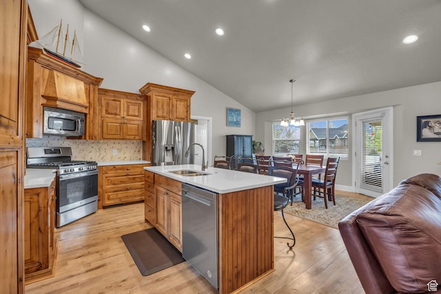 kitchen with light wood-style flooring, a sink, a notable chandelier, appliances with stainless steel finishes, and a breakfast bar area