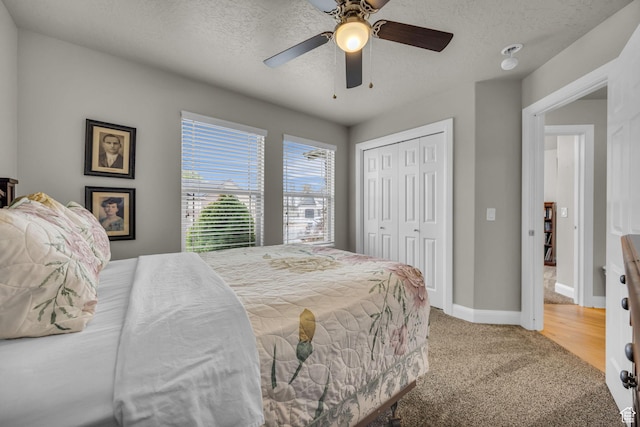 bedroom with a ceiling fan, a textured ceiling, a closet, baseboards, and carpet flooring