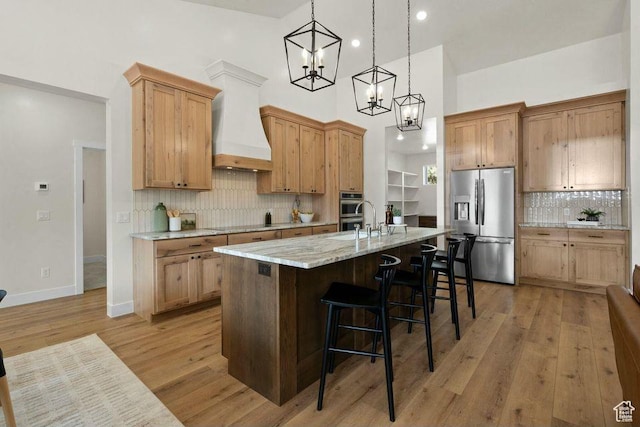 48 N Meadow Dr, Pine Valley, UT 84781 - kitchen with stainless steel appliances, a center island with sink, light wood-type flooring, custom exhaust hood, and a kitchen bar