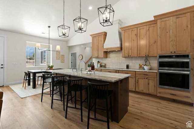 48 N Meadow Dr, Pine Valley, UT 84781 - kitchen featuring a kitchen island with sink, a notable chandelier, stainless steel double oven, decorative backsplash, and wood finished floors