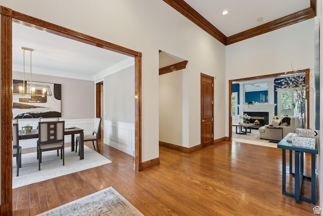 6391 S Shenandoah Park Ave E, Salt Lake City, UT 84121 - entryway with a wainscoted wall, a chandelier, wood finished floors, ornamental molding, and a lit fireplace