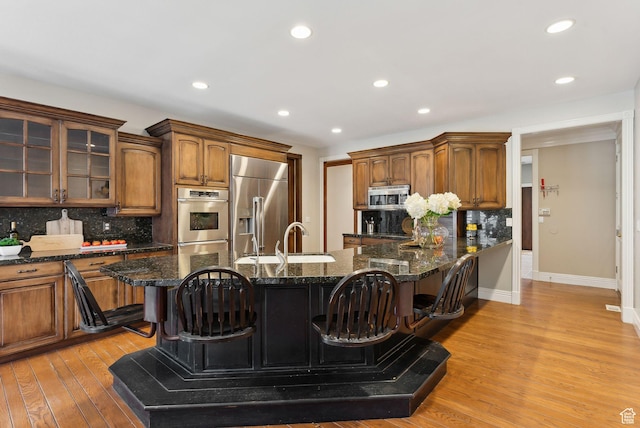6391 S Shenandoah Park Ave E, Salt Lake City, UT 84121 - kitchen with a sink, decorative backsplash, a breakfast bar area, light wood finished floors, and appliances with stainless steel finishes