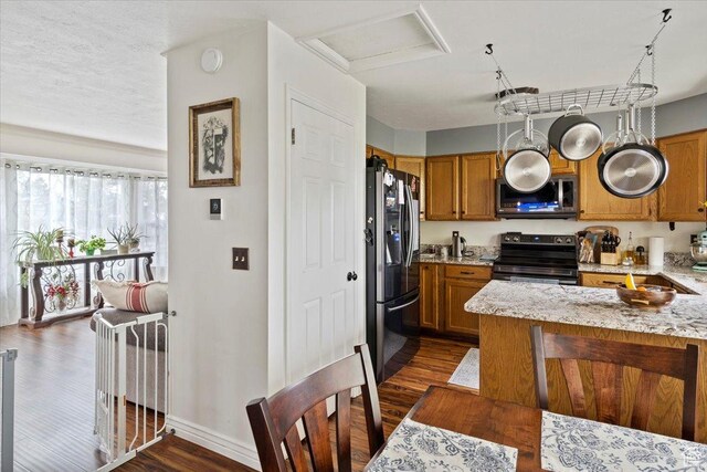 6241 S Barton Park Dr, West Jordan, UT 84081 - kitchen with dark wood-style floors, baseboards, brown cabinets, light stone countertops, and appliances with stainless steel finishes