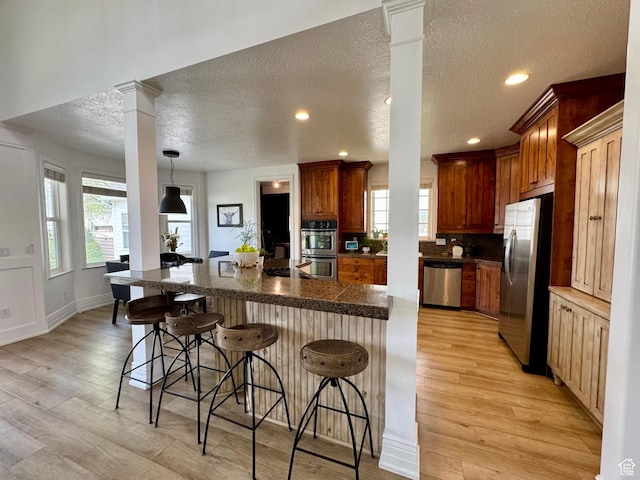 1844 W Heritage Ranch Dr N, Farr West, UT 84404 - kitchen featuring a healthy amount of sunlight, appliances with stainless steel finishes, a kitchen breakfast bar, and decorative columns