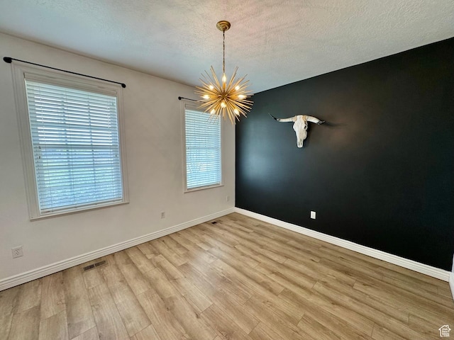 1844 W Heritage Ranch Dr N, Farr West, UT 84404 - spare room featuring an inviting chandelier, wood finished floors, visible vents, baseboards, and a textured ceiling