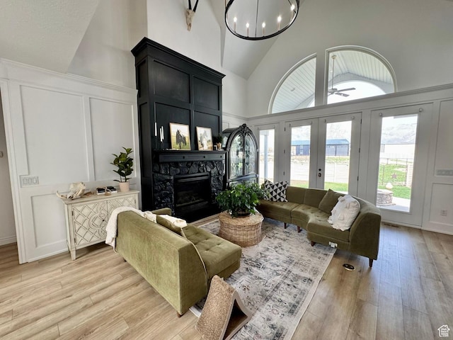 1844 W Heritage Ranch Dr N, Farr West, UT 84404 - living area featuring light wood-style flooring, a wainscoted wall, high vaulted ceiling, a decorative wall, and a fireplace