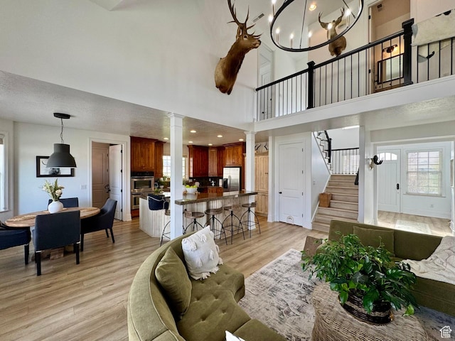 1844 W Heritage Ranch Dr N, Farr West, UT 84404 - living area featuring a high ceiling, ornate columns, an inviting chandelier, light wood-type flooring, and stairs