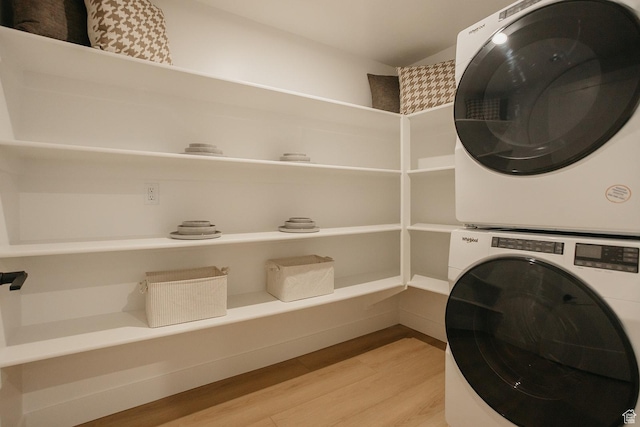 washroom with stacked washer / drying machine, laundry area, and light wood-type flooring
